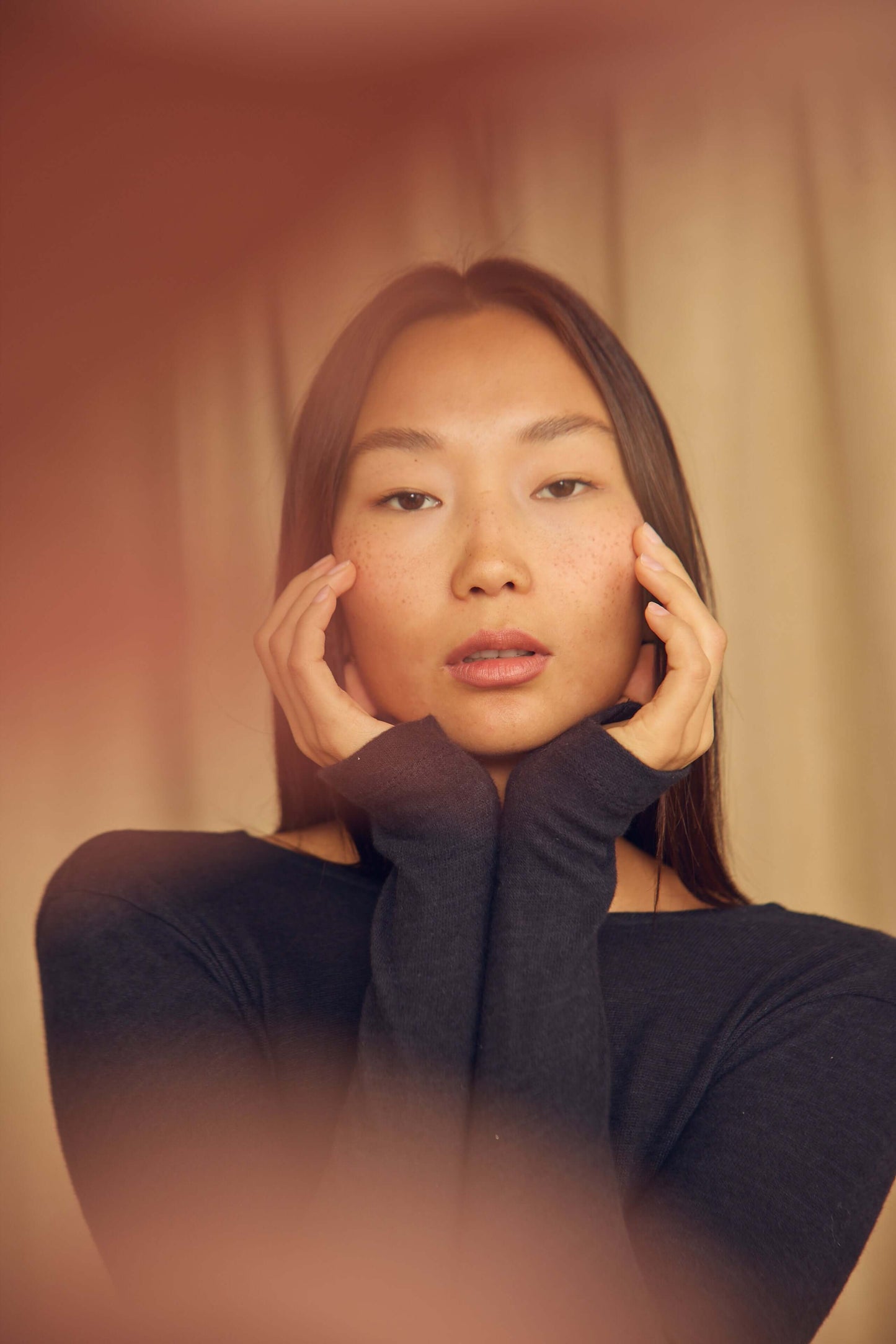 Model wearing a Black Wool Wrap Top with thumb holes, showcasing the elegant design and soft fabric in a close-up portrait.