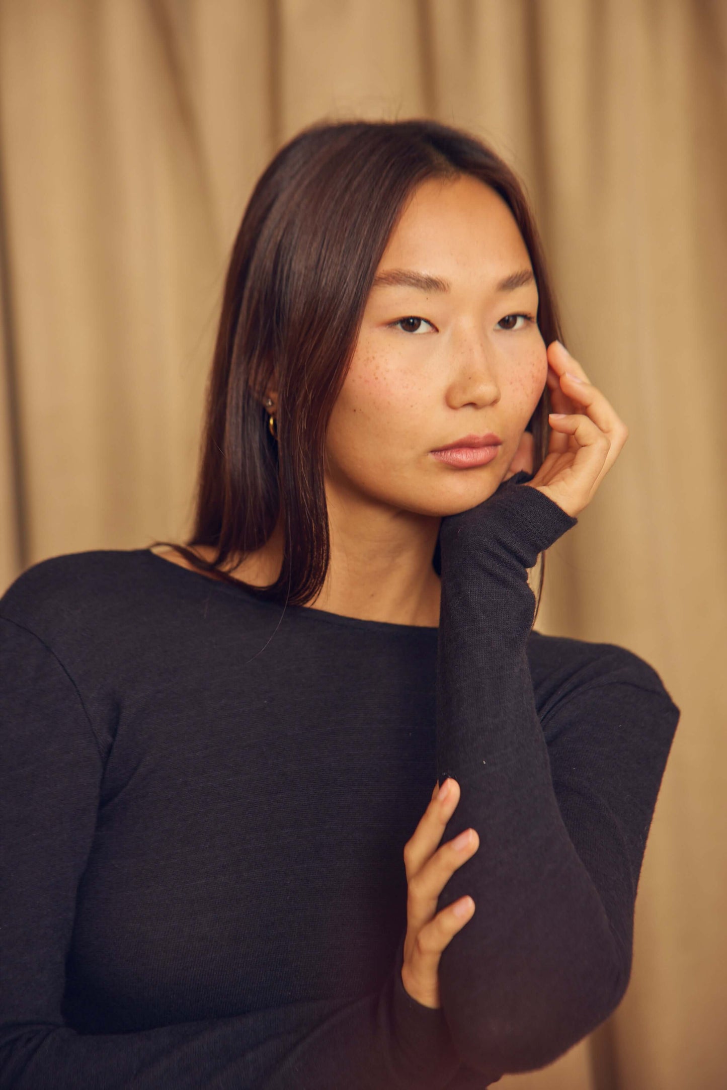 Model wearing a Black Wool Wrap Top with Thumb Holes, showcasing a stylish feminine look.