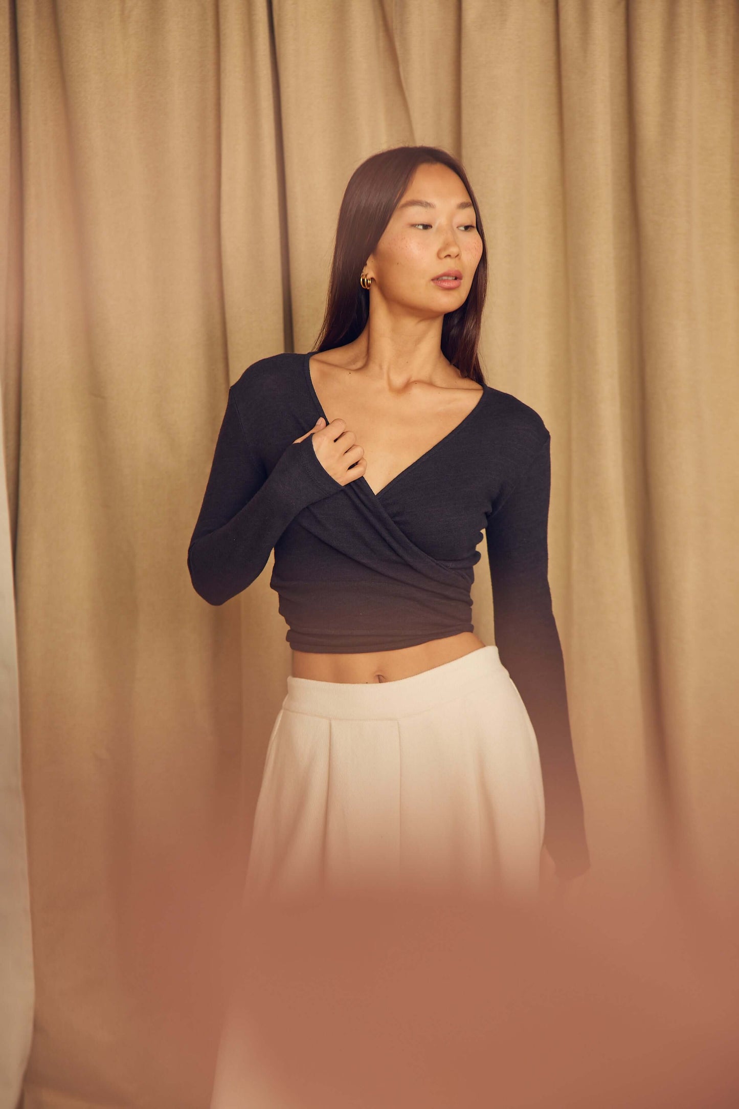 Model wearing a Black Wool Wrap Top with thumb holes, styled with a flowy skirt, showcasing its elegant design.