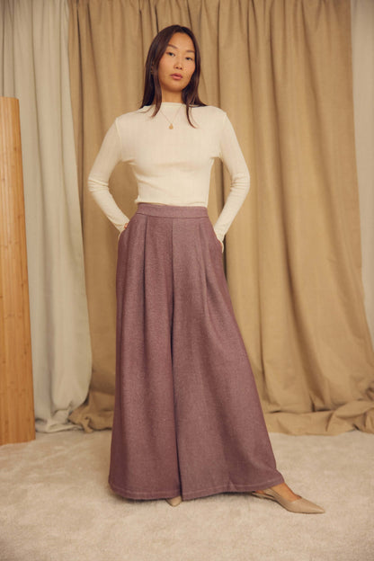 Model wearing Ecru Lyocell Ribbed Long Sleeve Top paired with wide-leg trousers in a stylish indoor setting.