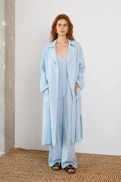 Lightweight Organic Cotton Trench Coat in Pale Blue modeled by a woman in a relaxed fit, showcasing its versatile design.
