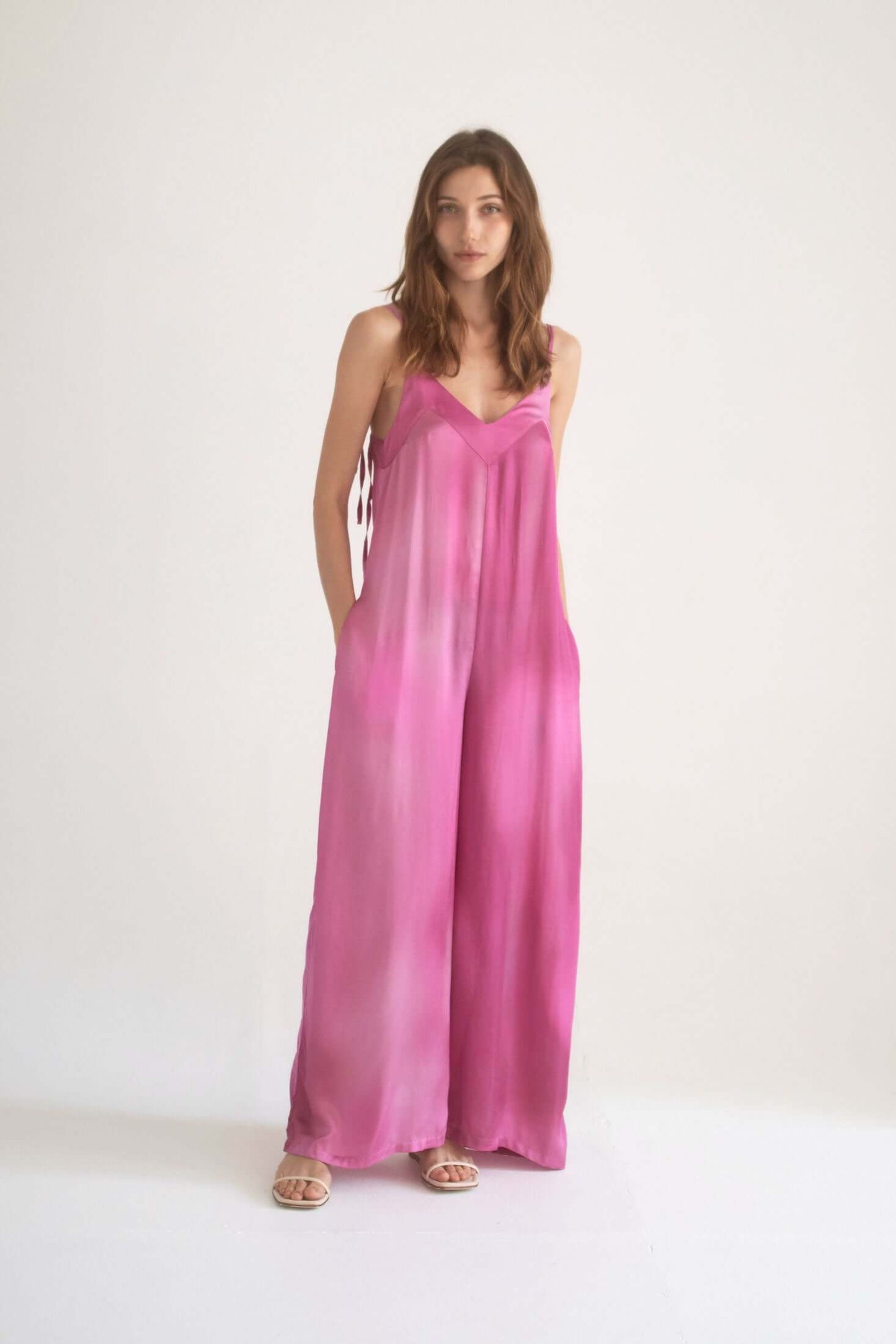 Model wearing a Printed Wide Jumpsuit in pink with adjustable straps and side pockets.