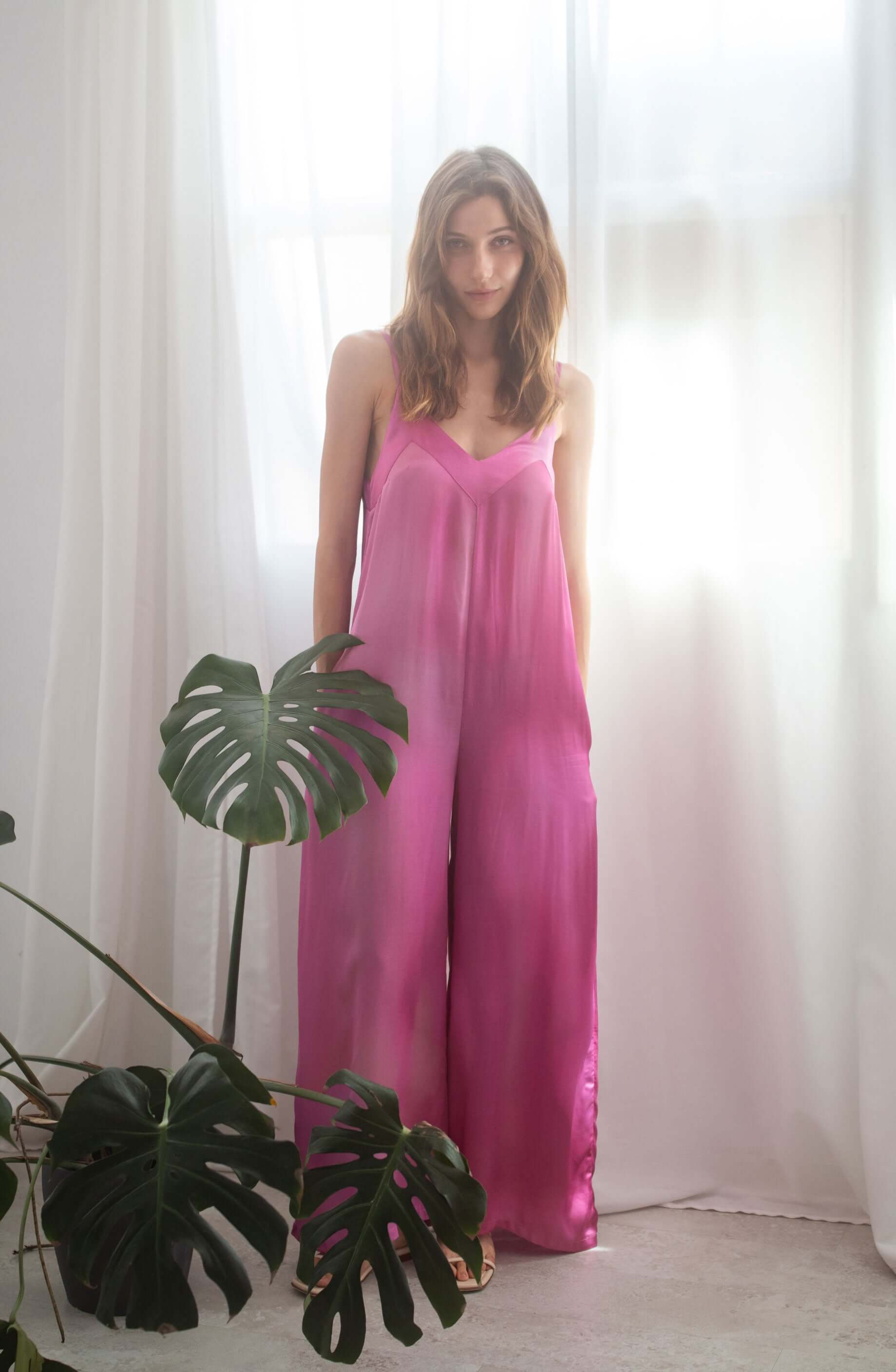 Model wearing a Printed Wide Jumpsuit in pink color, showcasing adjustable shoulder straps and side pockets.